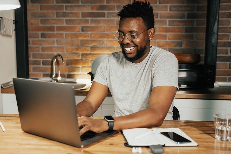 a person using their laptop on a wooden table while smiling