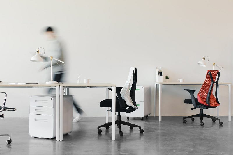 an office area with white desks and swivel chairs