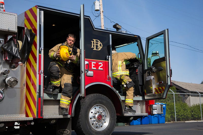 Nine-year firefighting veteran John McDonald – left – and Acting Captain Richard Dowdy – right – exit a fire truck as if they were arriving at the scene of a fire while training at the Bellingham Fire Department Training grounds on Tuesday, April 26.