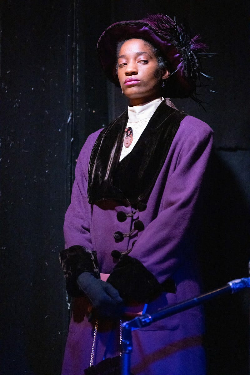 A young woman with brown skin in early 20th century clothes, including a feathered hat and purple coat