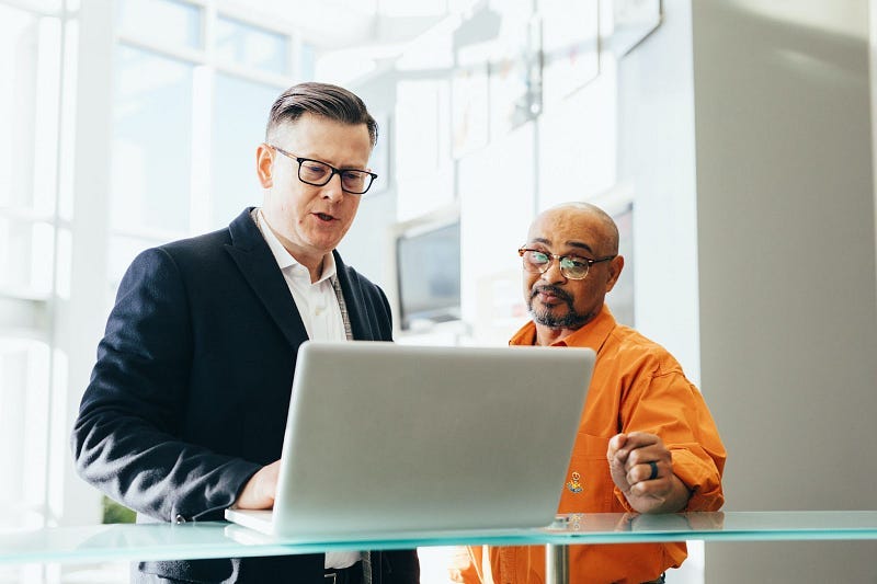 a man explaining in front of a laptop with a person