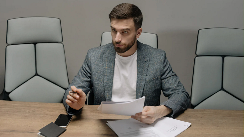 The man sitting on the other side of the table raises his hand to make a point.