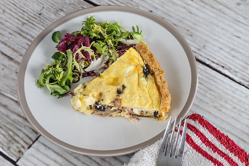 Photogaph of a slice of quiche on a plate.