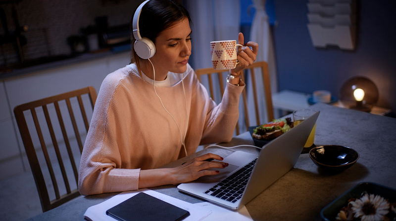 A woman wearing headphones works calmly at her laptop.