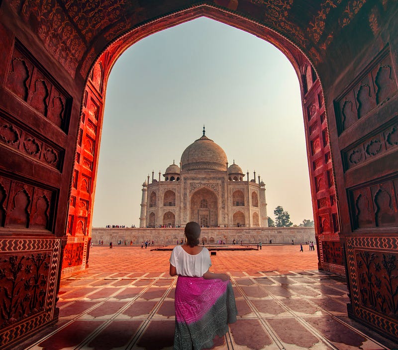 Woman with long colourful dress in front of Taj Mahal in India.