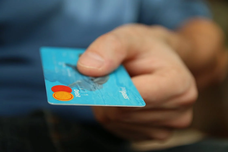 A left hand holding a debit card 