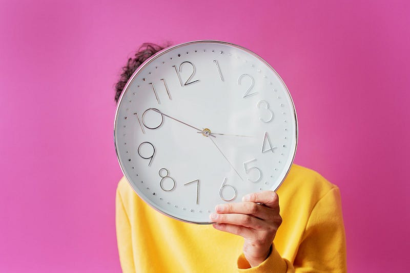a person covering their face with a wall clock