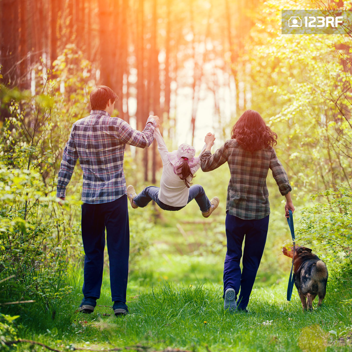 Stock Photo - Happy family walking with dog in the forest