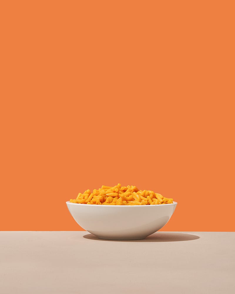 Bowl of macaroni and cheese sitting on a table.