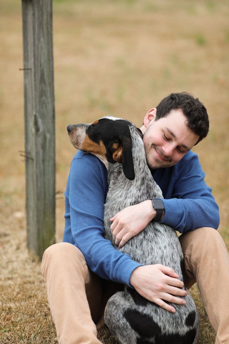 Blue sweater dressed owner hugging his dog with a happy smile face.