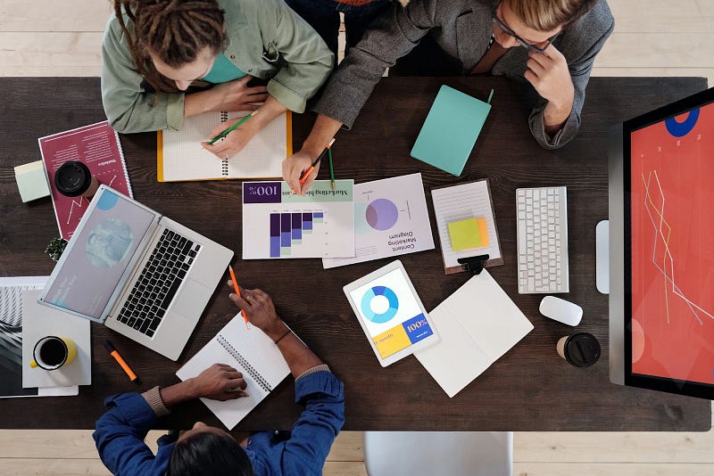 three people reviewing their organizational development data on a long wooden table