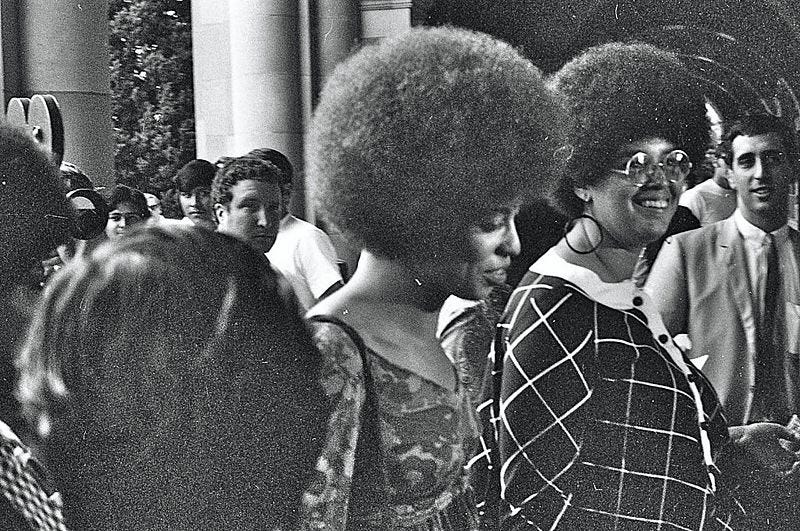 Photo of Kendra Alexander (with glasses) and Angel Davis (at the center) as they enter the Royce Hall in UCLA. 1969. Angel did her first lecture there.
