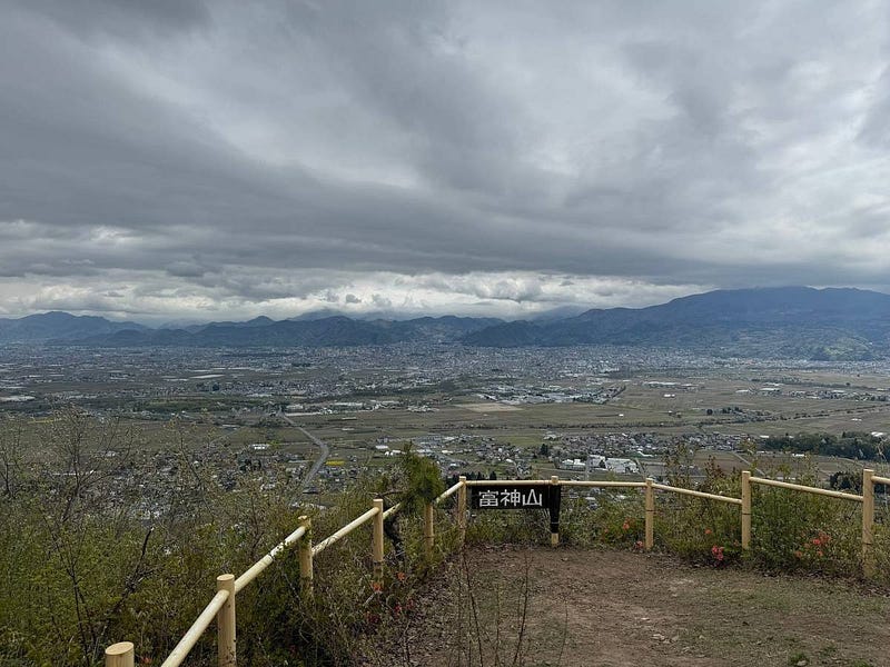The view from the summit of Togami-yama with Yamagata City in the distance. Mountains under a grey sky complete the look.