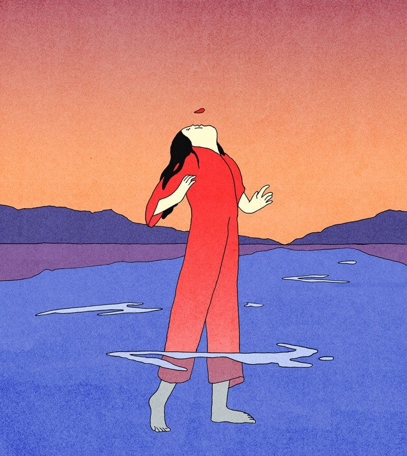 A person standing in the water with mountains in the background. They are dressed in a red jumpsuit with the head tilted up blowing on a petal.