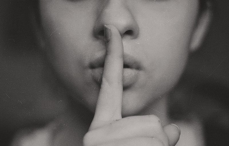 I’m so bad at keeping secrets! That’s why the woman in this photo is holding a finger over her lips shushing me.