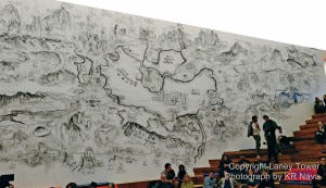 Museum attendees sit and stand beneath the massive Art Wall featuring Qiu Zhijie's "World Garden".