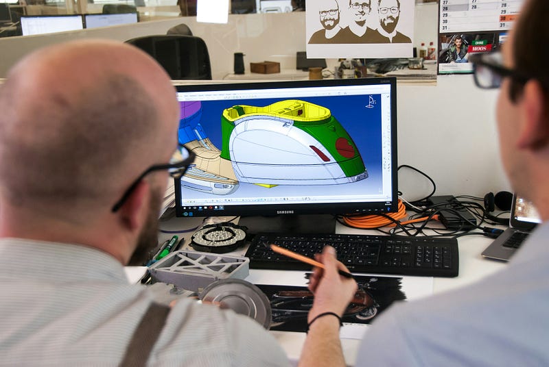 two designers looking at a computer screen displaying a modern construction project