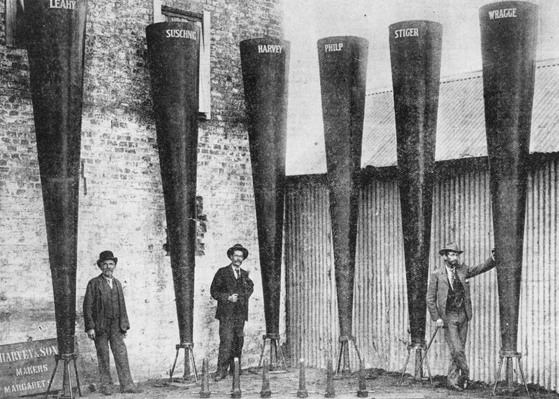 Three men stand among six tall cones, standing vertically, about 15-feet high.