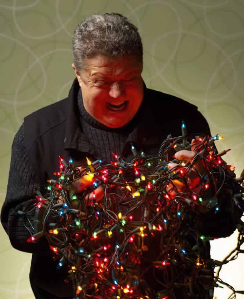 A frustrated man trying to disentangle Christmas lights