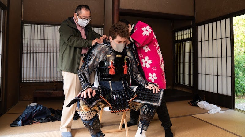 Local government staff work to dress Donny Kimball in samurai armor in Akizuki, Fukuoka Prefecture