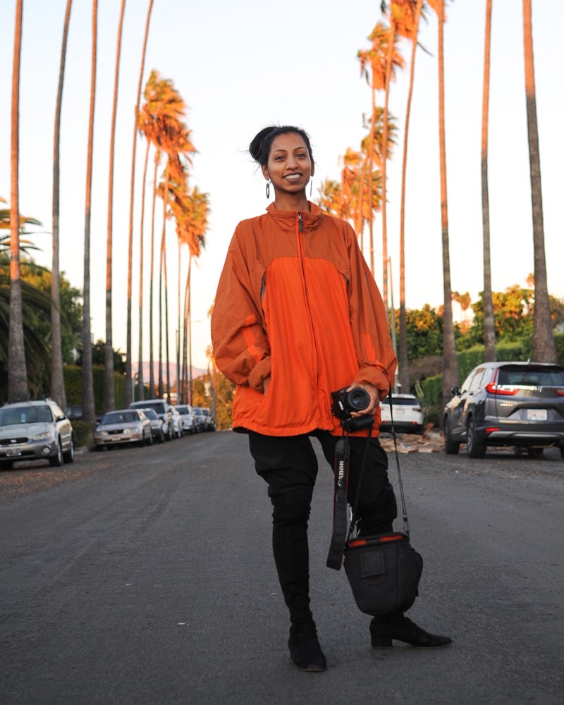 Bukht standing on a palm-lined street in LA with her camera in hand.