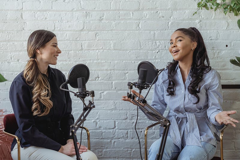 Two women in front of podcast microphones having a conversation
