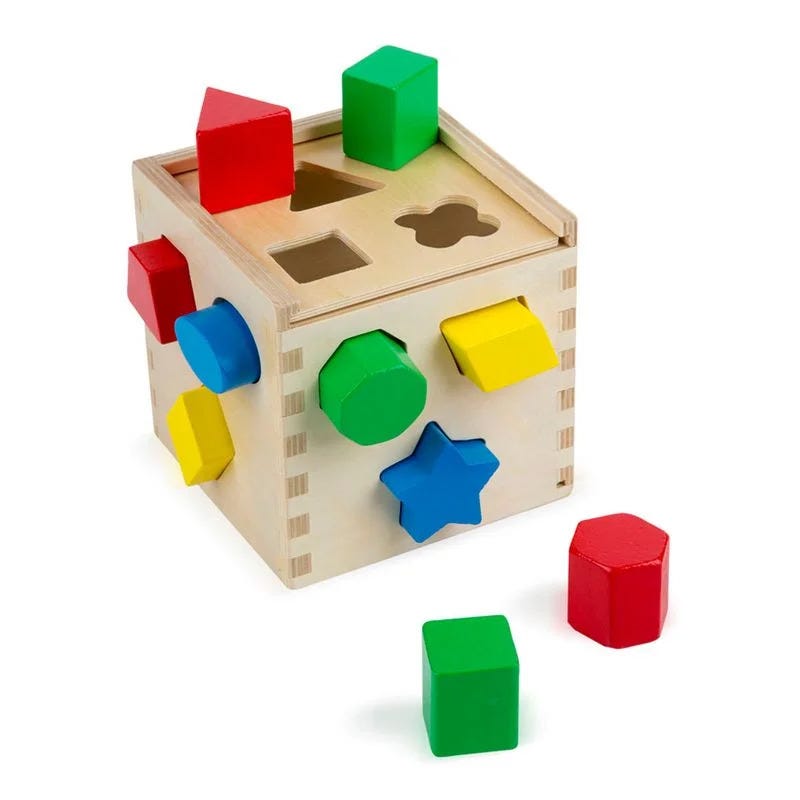the classic “pegs into holes” kiddie game, a wooden box with holes having different shapes and different colored pegs, some of them already fitted into some of the holes