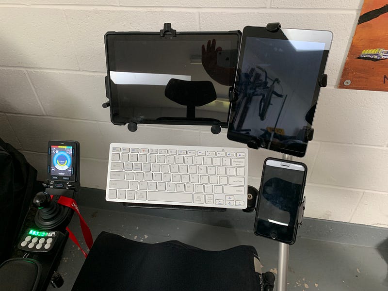 A Surface Pro, iPad and iPhone all mounted side-by-side on a powered wheelchair.