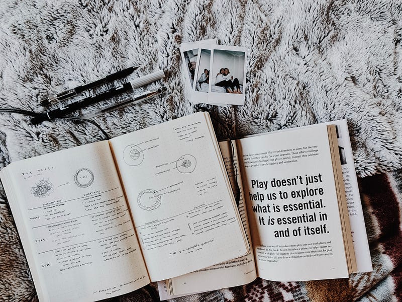 A journal and inspirational book laid out on a cozy rug with pens and photos nearby.