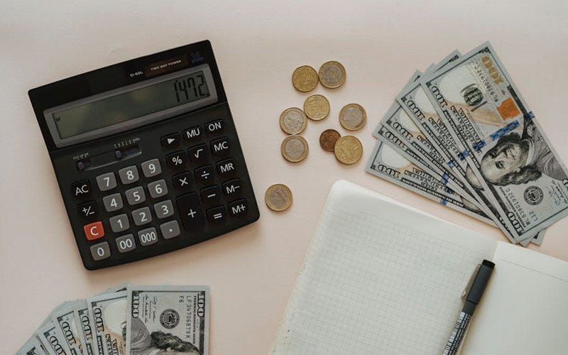 Black Calculator beside Coins and Notebook