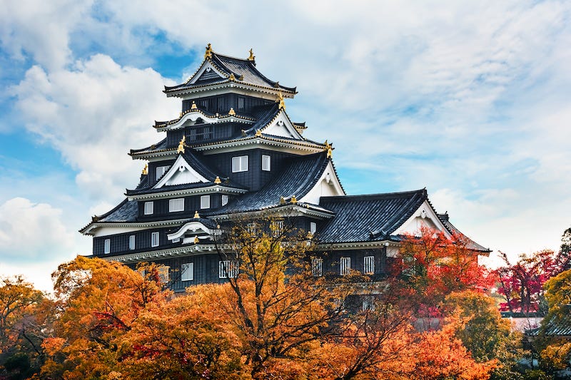 Okayama Castle set against a number of vibrant trees during the months of autumn