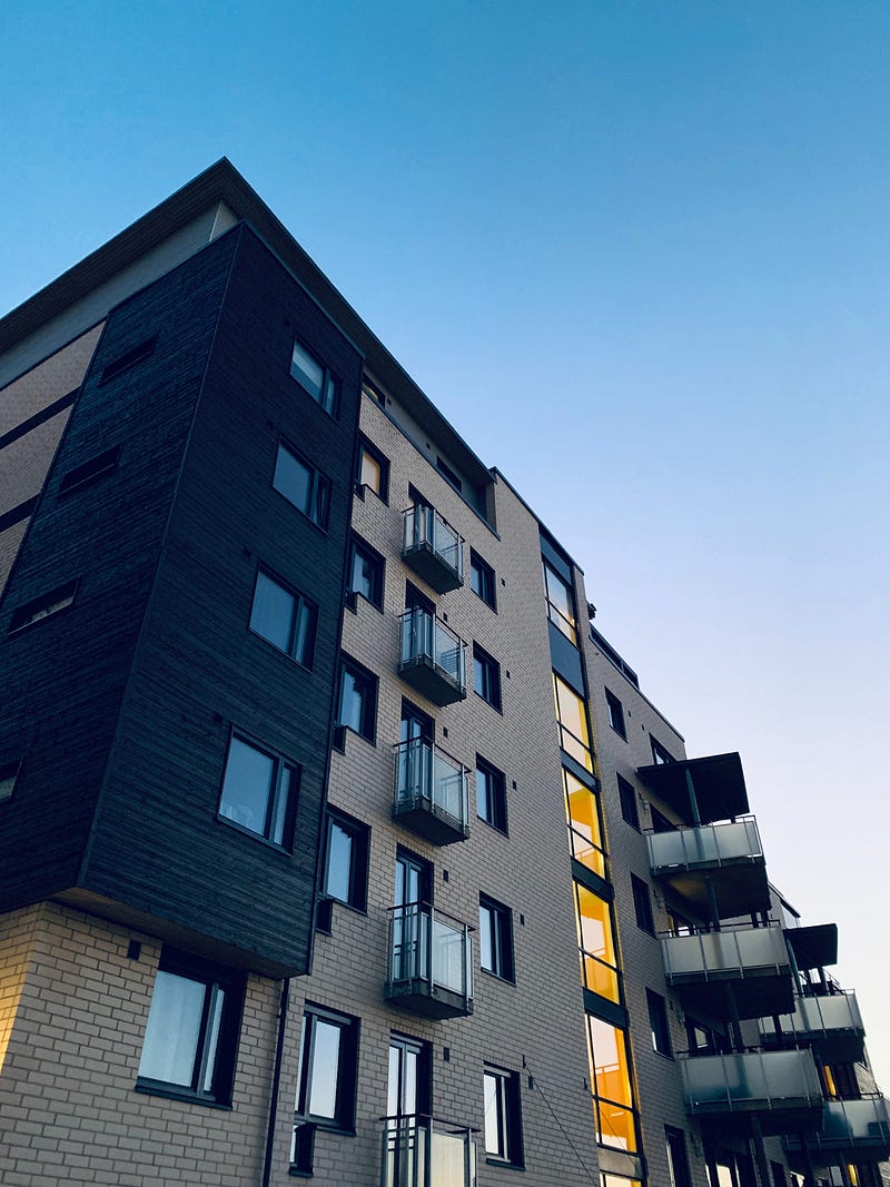 Grey apartment building against blue sky.