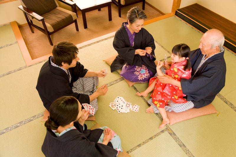 A family plays a game of cards while staying at a ryokan in Japan