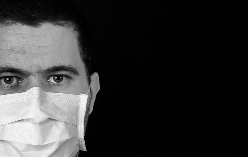Black and white image of a person wearing a cloth medical mask over nose and mouth, set against a black background