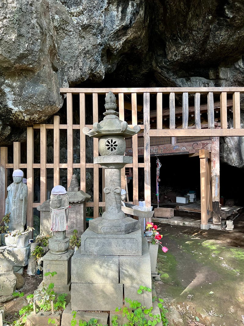 Rugged cave mouth with wooden framework. Statues in the font.