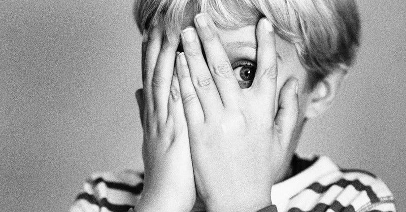 Image of boy covering his eyes with his hands in fear.