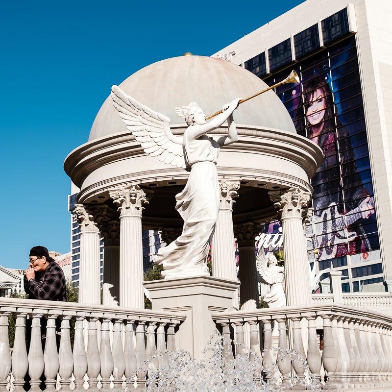 A gaudy scene in Las Vegas with a man smoking a cigarette in the foreground.