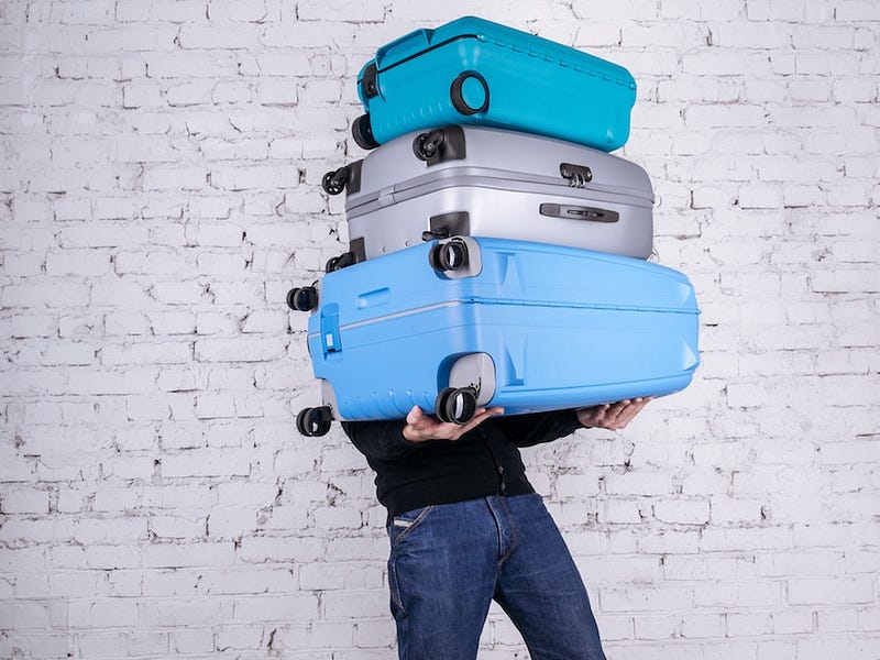 A man struggles to carry a ton of large suitcases