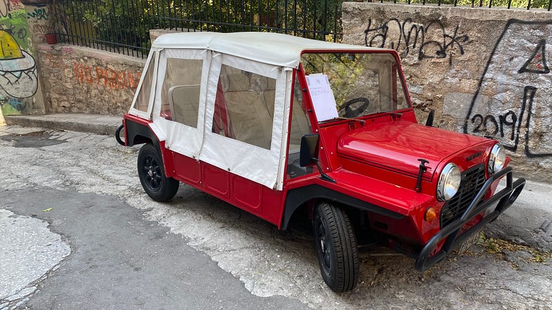 A red mini moke car parked on a street