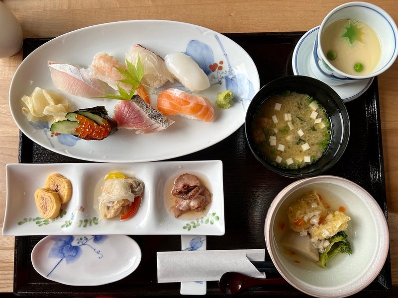 A plate of mixed sushi, soup, and other side dishes.