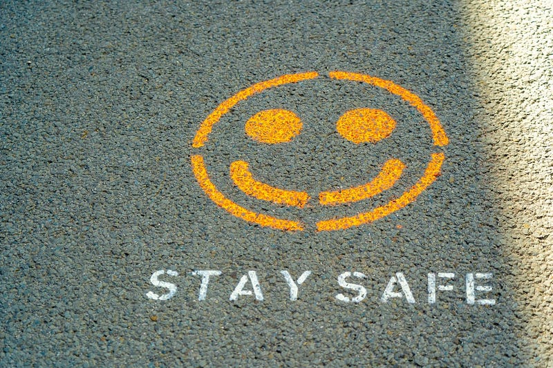 a yellow smiley face outline on a road and the words stay safe printed below it