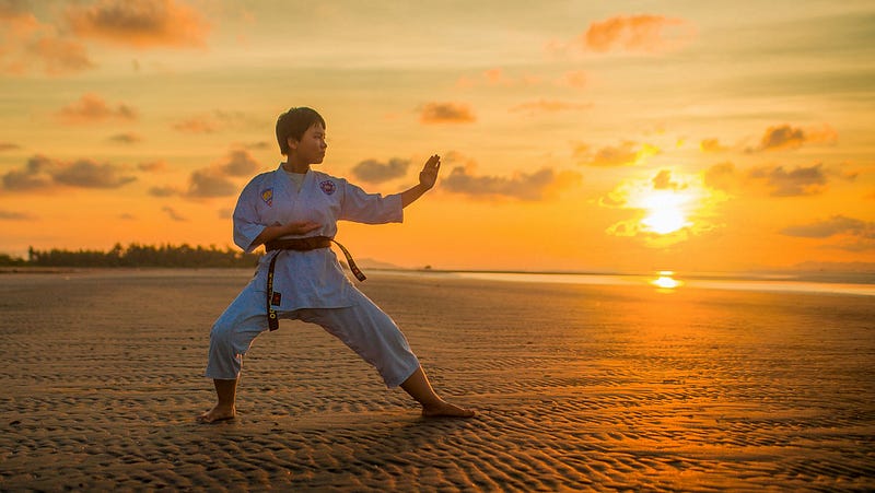 A person practicing martial arts on the beach