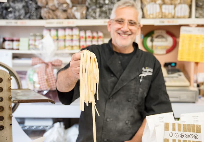 man holding up homemade pasta