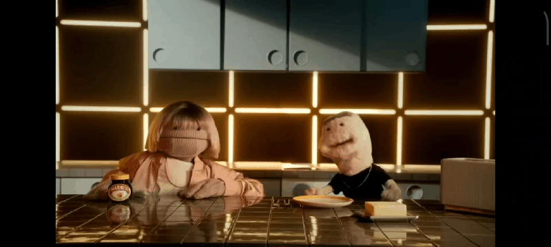 A GIF of two puppets sitting at a breakfast table. One grabs a jar of Marmite.