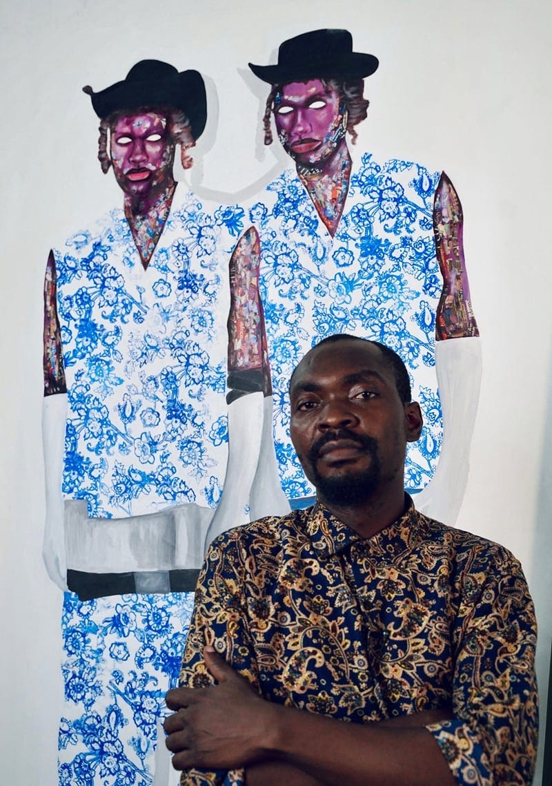 Taku stands in front of one of his portraits, featuring two black men in white clothing with blue floral prints.