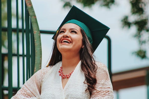 Young woman graduating from college and smiling.