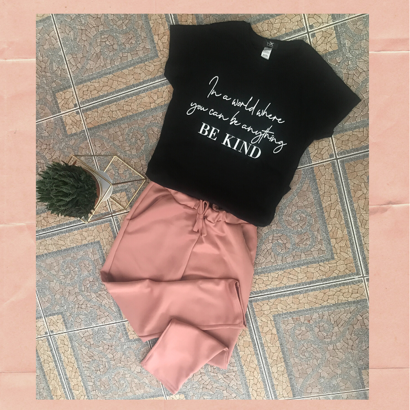 Black t-shirt with slogan: In a world where you can be anything be kind and pink joggers