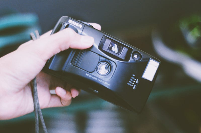 a hand holding a disposable camera