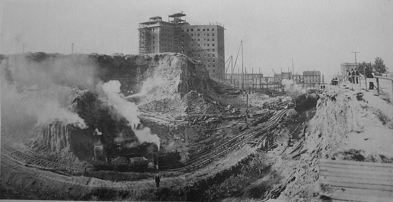 A train line through a landscape of excavation and construction.