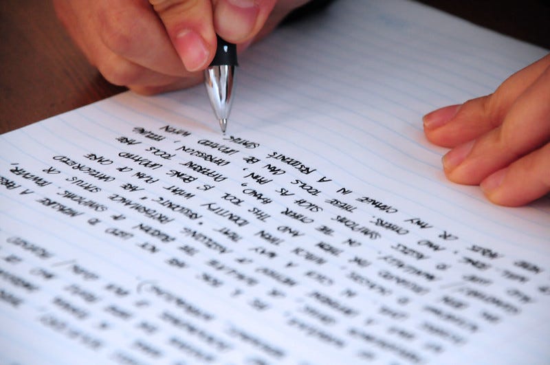A person hand writing on a lined page